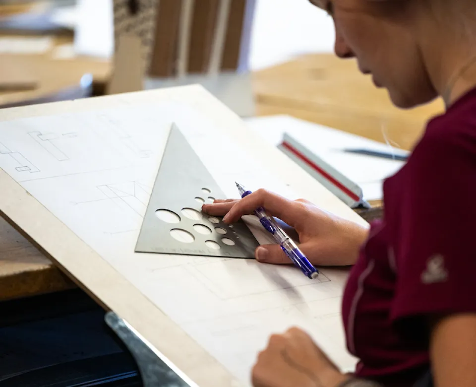 Student working with drafting tools in architecture studio.