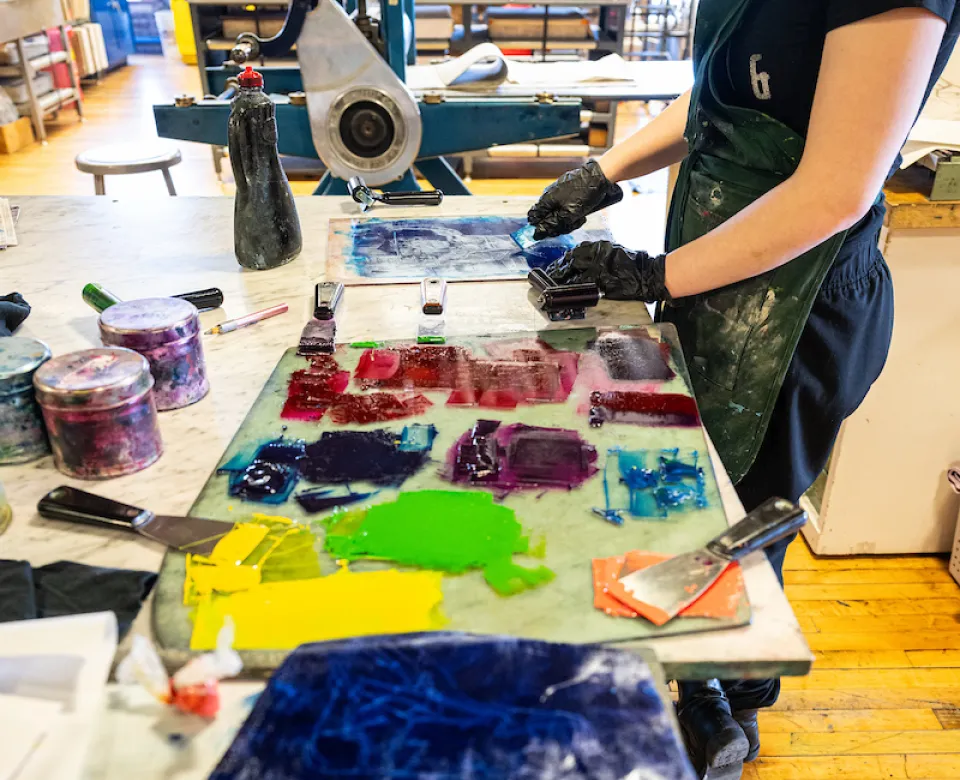 Student working in stdio with paint colors at table.
