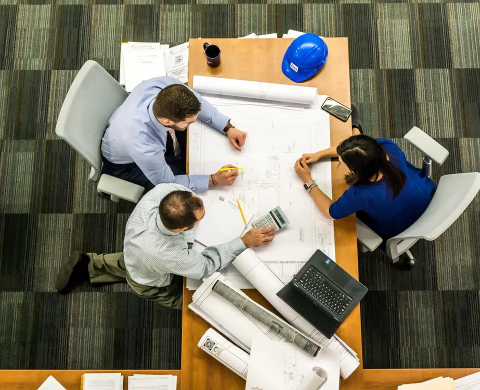 Group of three professionals working on project plans at a table. View from above. 