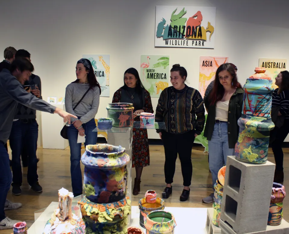 Students look at colorful ceramics in the Gallery 