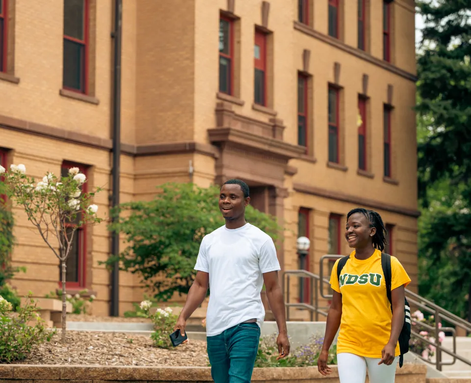 Two students talking as the walk on campus on a clear day