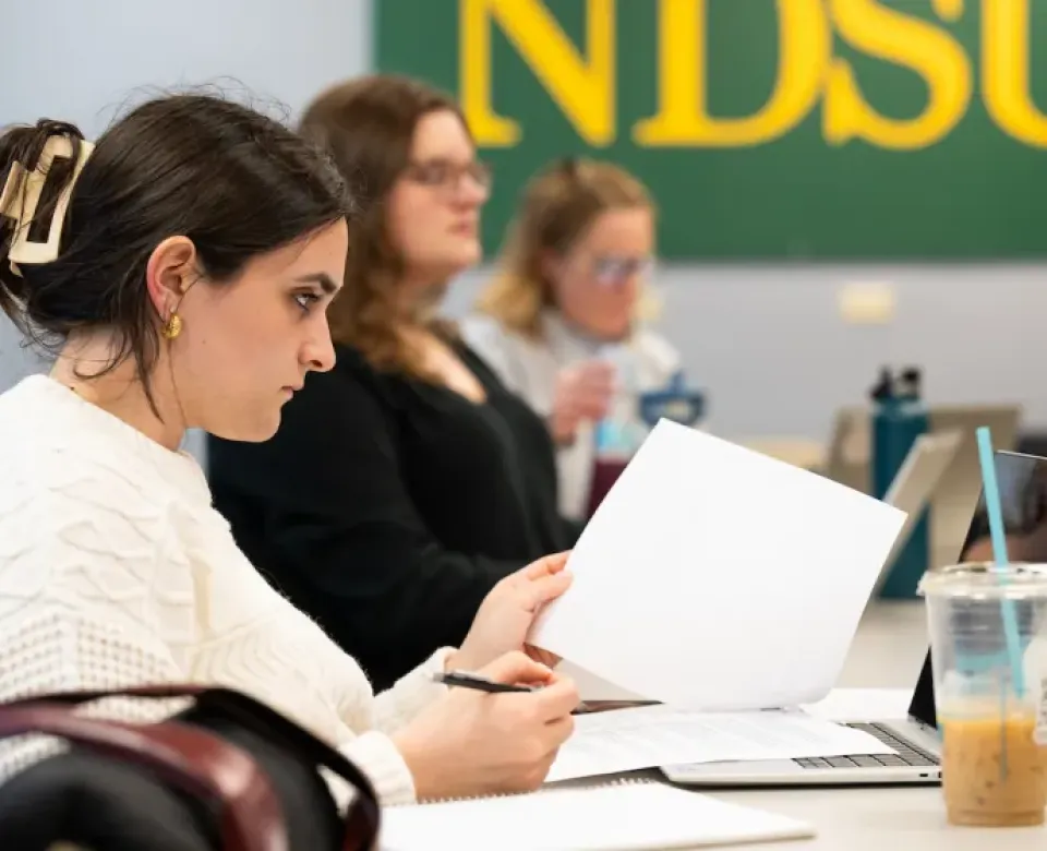 Student sitting at table working with pen and paper.