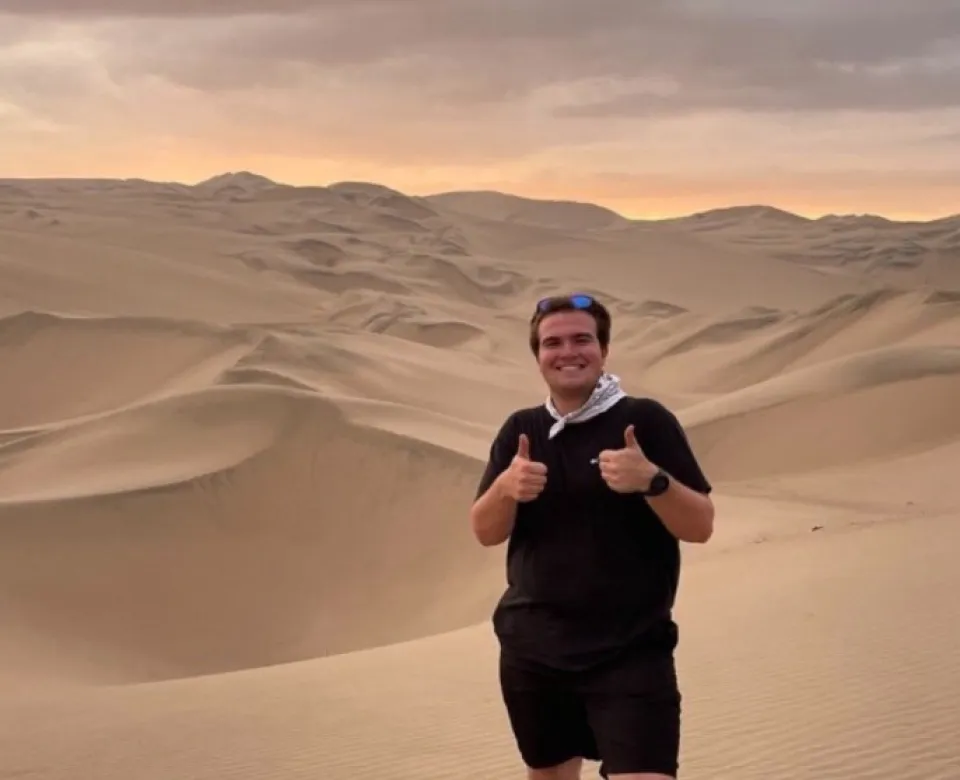 A person giving a thumbs up in a vast dessert