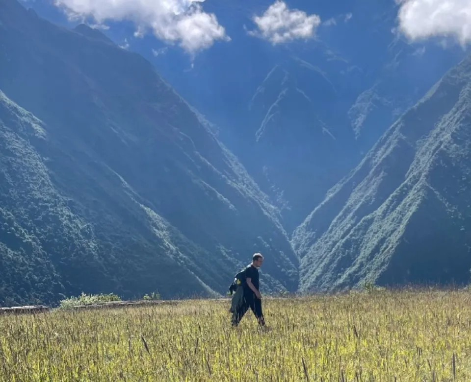 Person walking through vast field with mountain range in the background