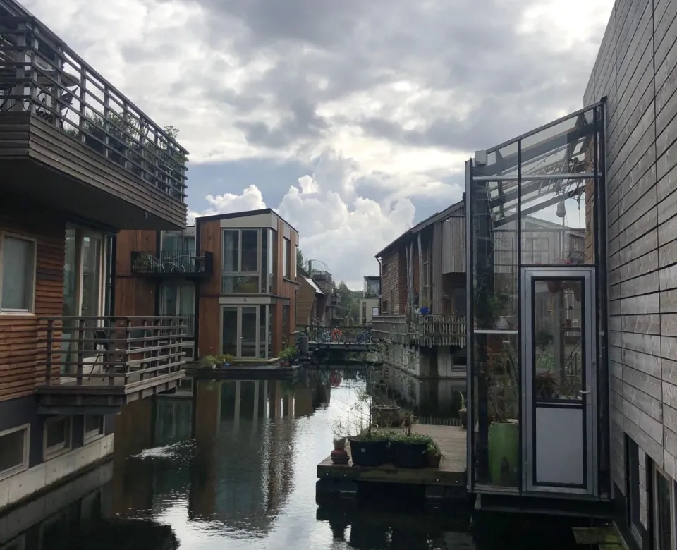 Scenic shot of the center of a river in Amsterdam with floating houses on each side.