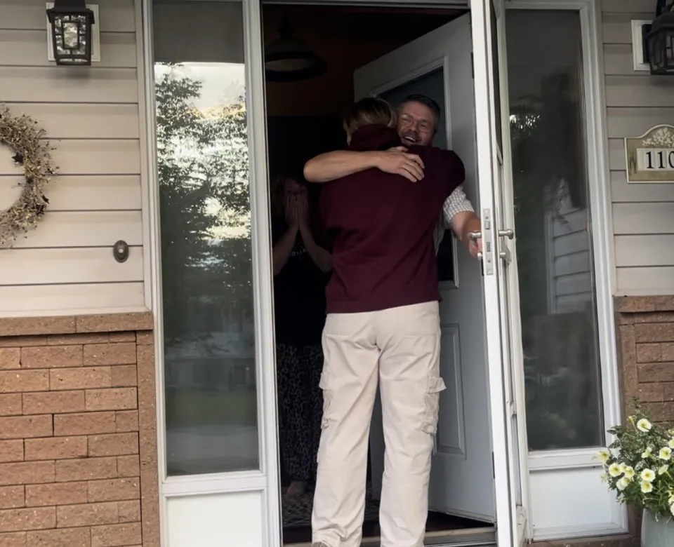 Student being embraced by a family member at the door