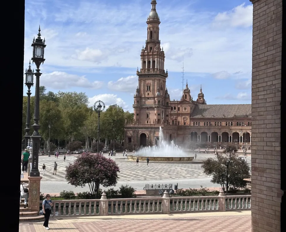 fountain in the middle of a large European plaza in front of church
