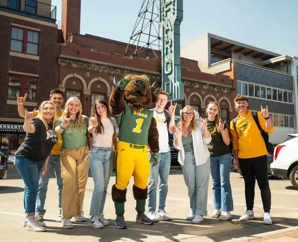 group of NDSU students standing in front of the Fargo Theatre sign with Thundar, the NDSU mascot