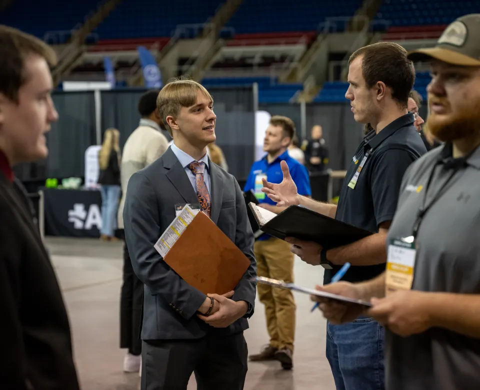 A student dressed in a suit talks to an employer