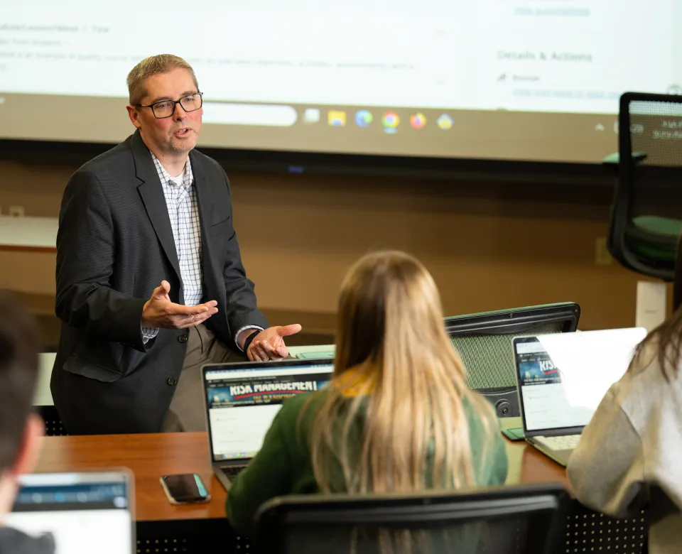 A faculty member talks with students in a classroom