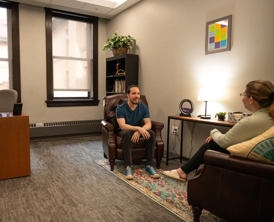 A student sits across from a staff member in an office