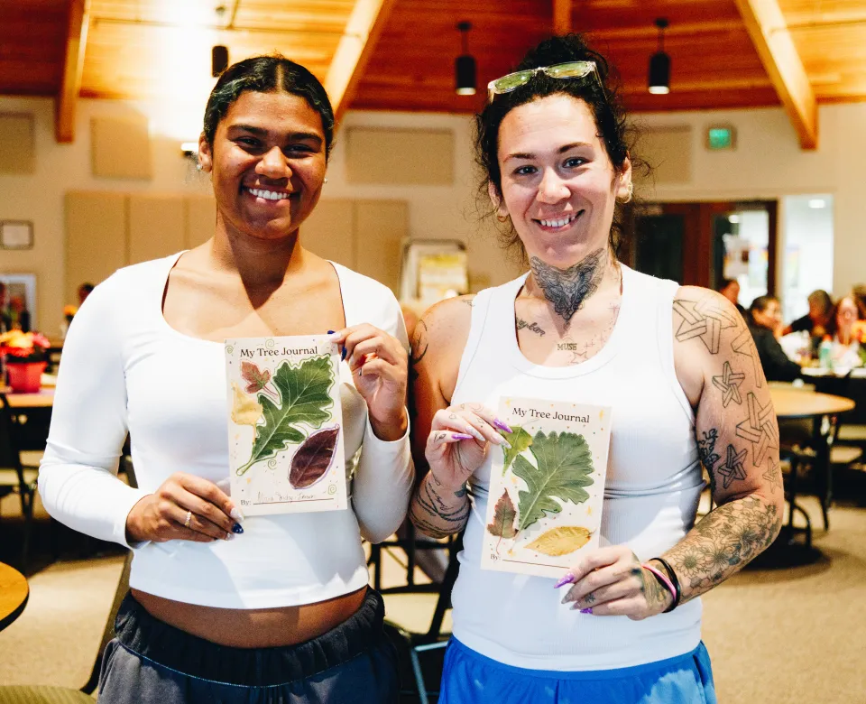 Two early childhood educators show off their tree journals.