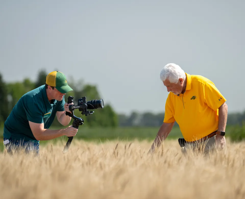 NDSU videographer Dan Erdmann works in the field with faculty member Elias Elias