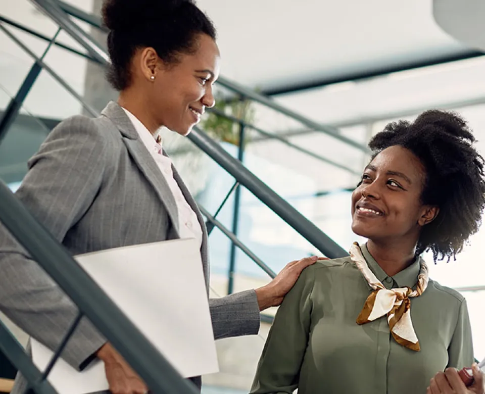 Two women on the stairs in business suits smiling