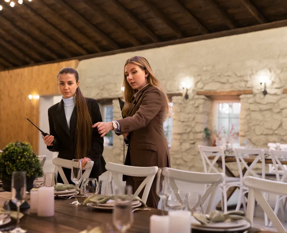 Two women at a venue lighting candles and discussing arrangements.