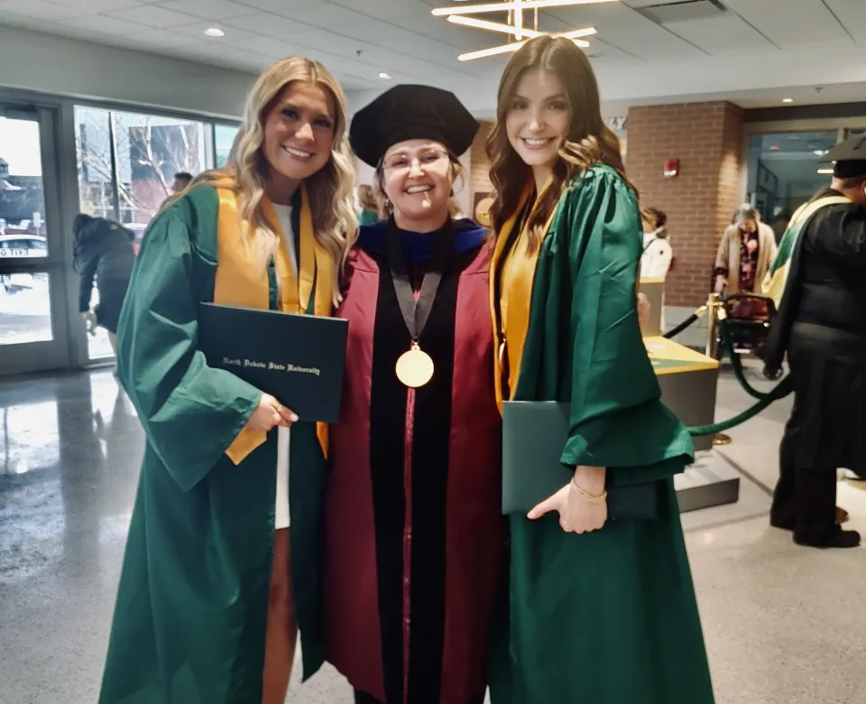 Students posing with faculty wearing graduation gowns.