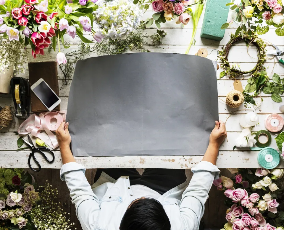 Flower shop worker arranging flowers from an array of options on a table