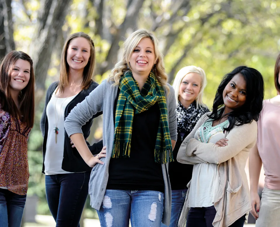 Student wearing a NDSU Tartan scarf while standing with a group of students.