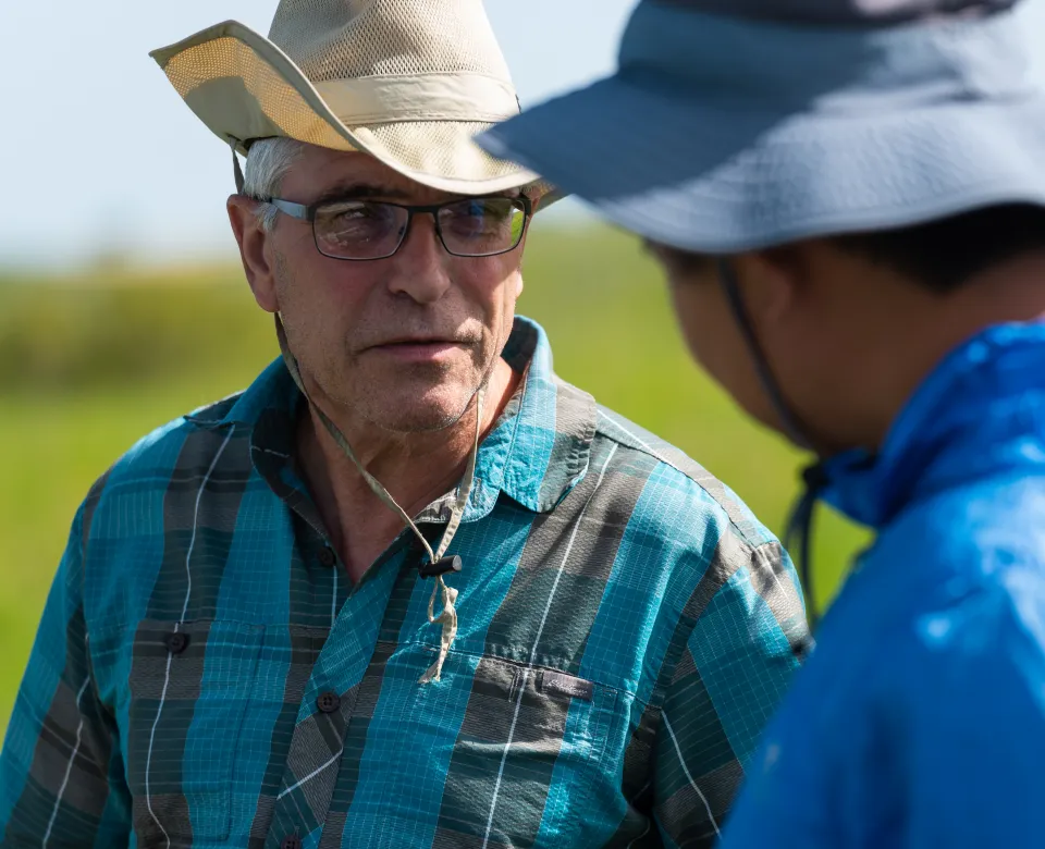 Dr. Otte talking to a research student in a green grassy field.