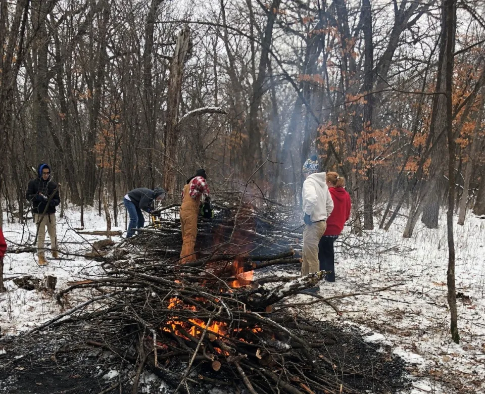 Students burning a large mound of tree branches.