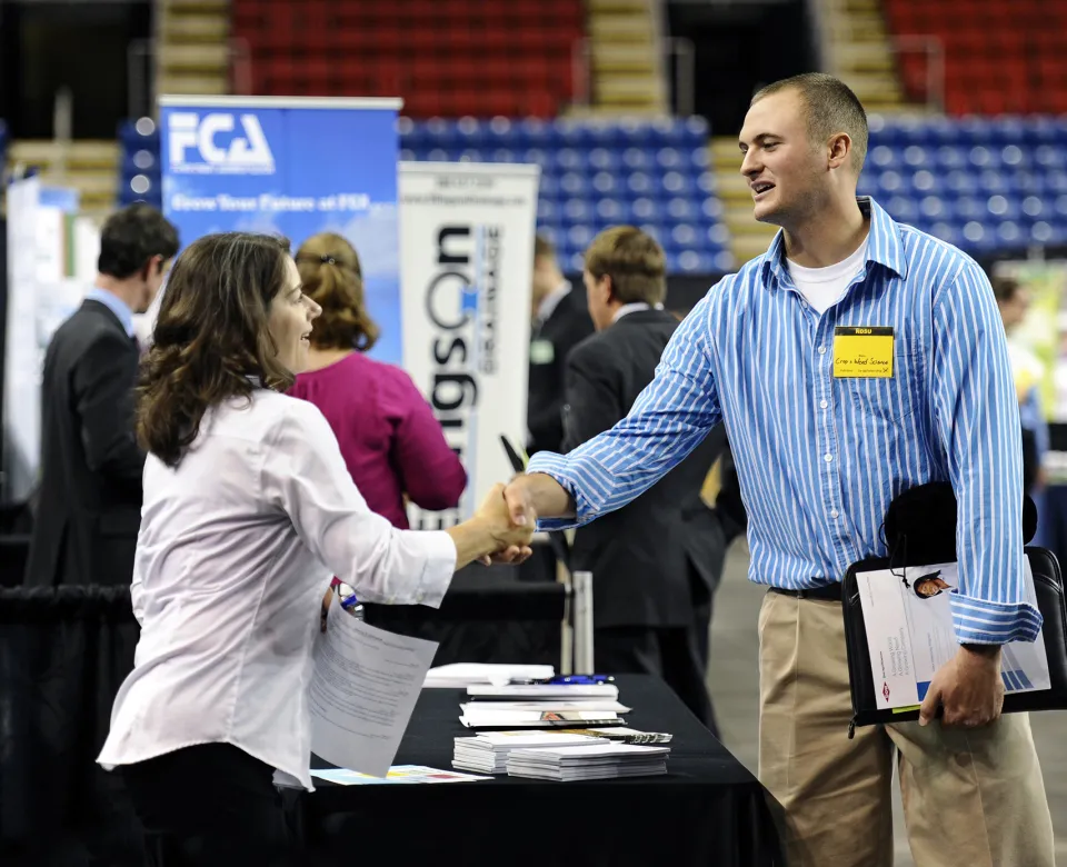 Student shaking hands with employer at job fair.