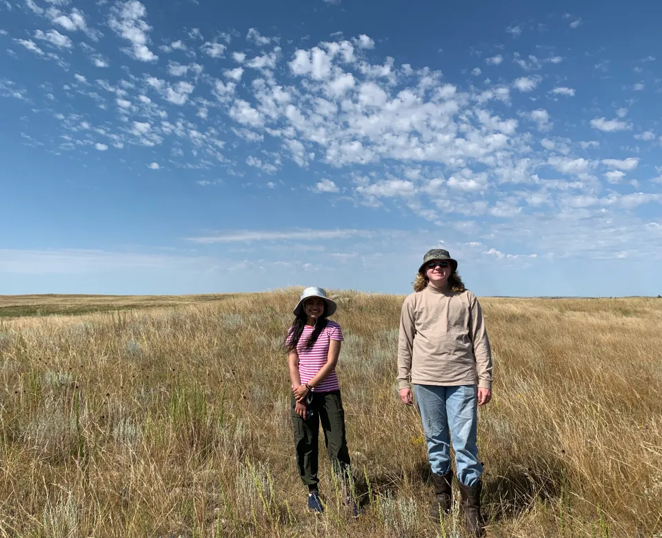 Two researchers standing in a grassy field.