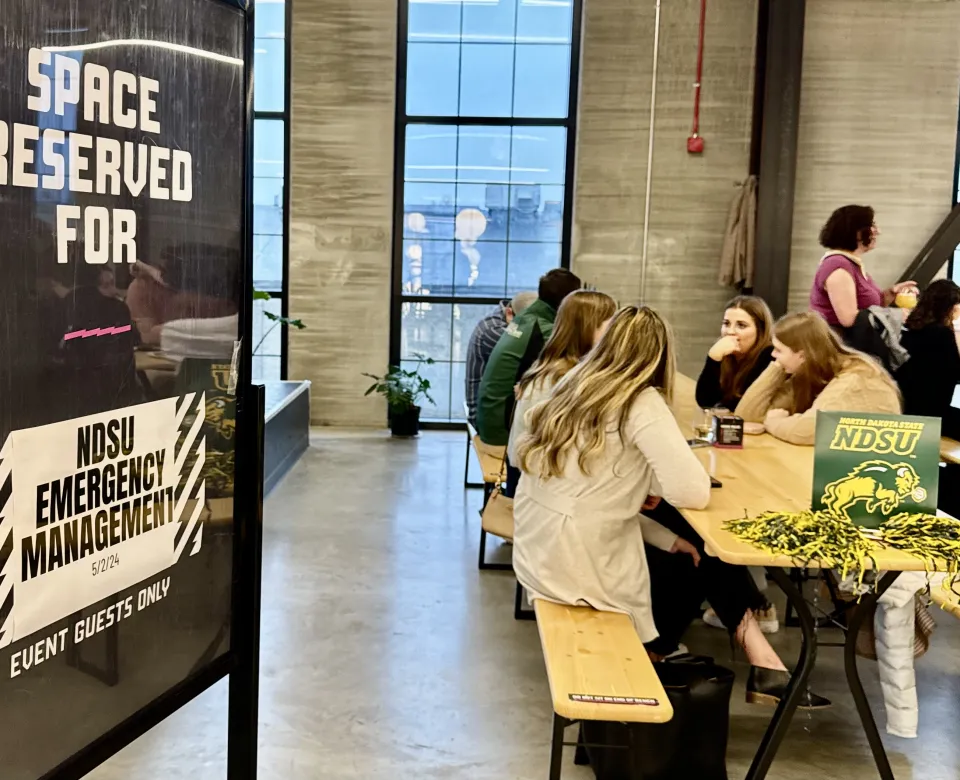 Students sitting at a long rectangular table talking.