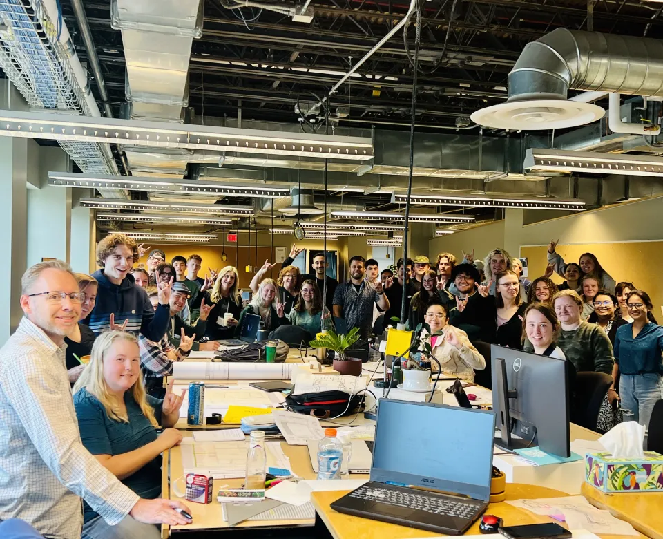 Large group of people gathered in the studio, all smiling at camera.