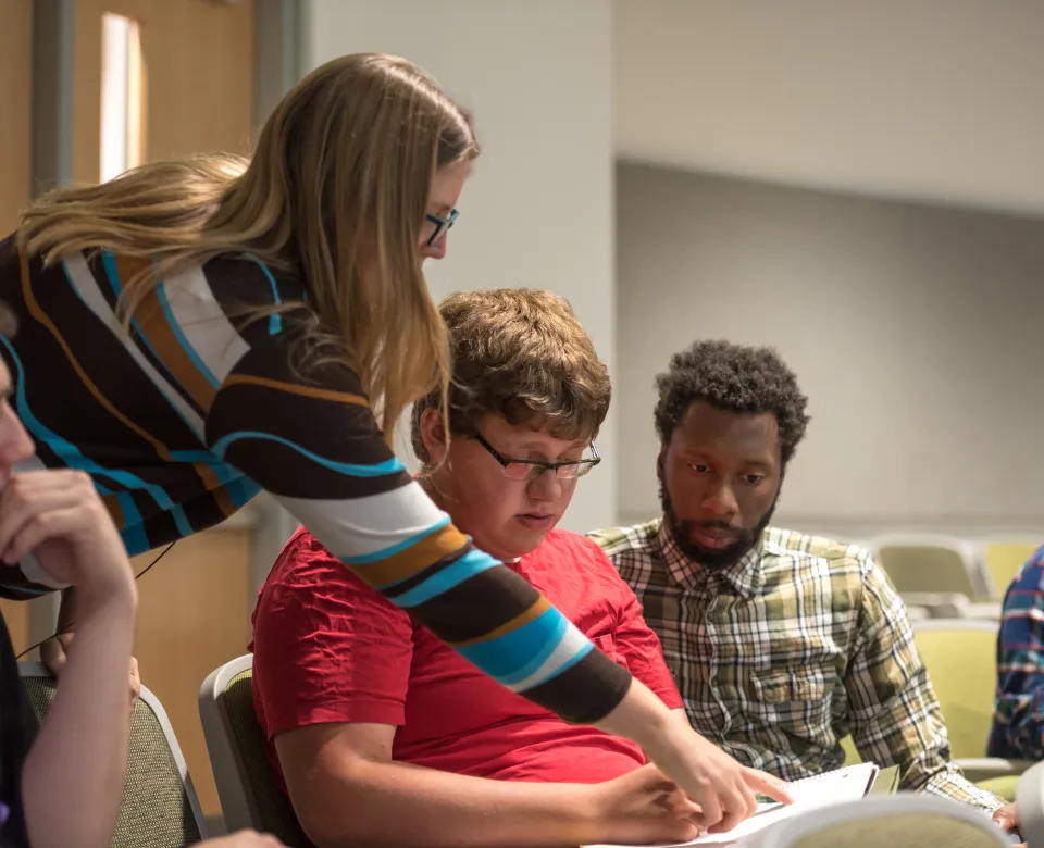 Faculty working with students in a classroom setting.