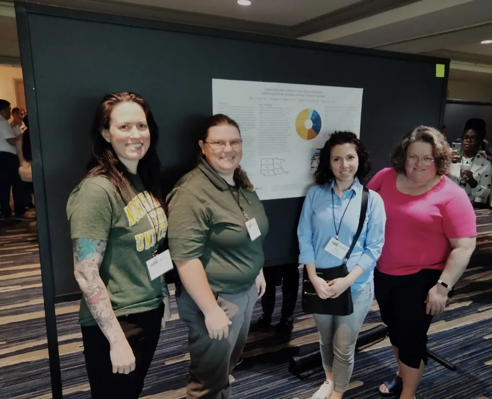Team of researchers standing in front of research poster, smiling confidently at the camera