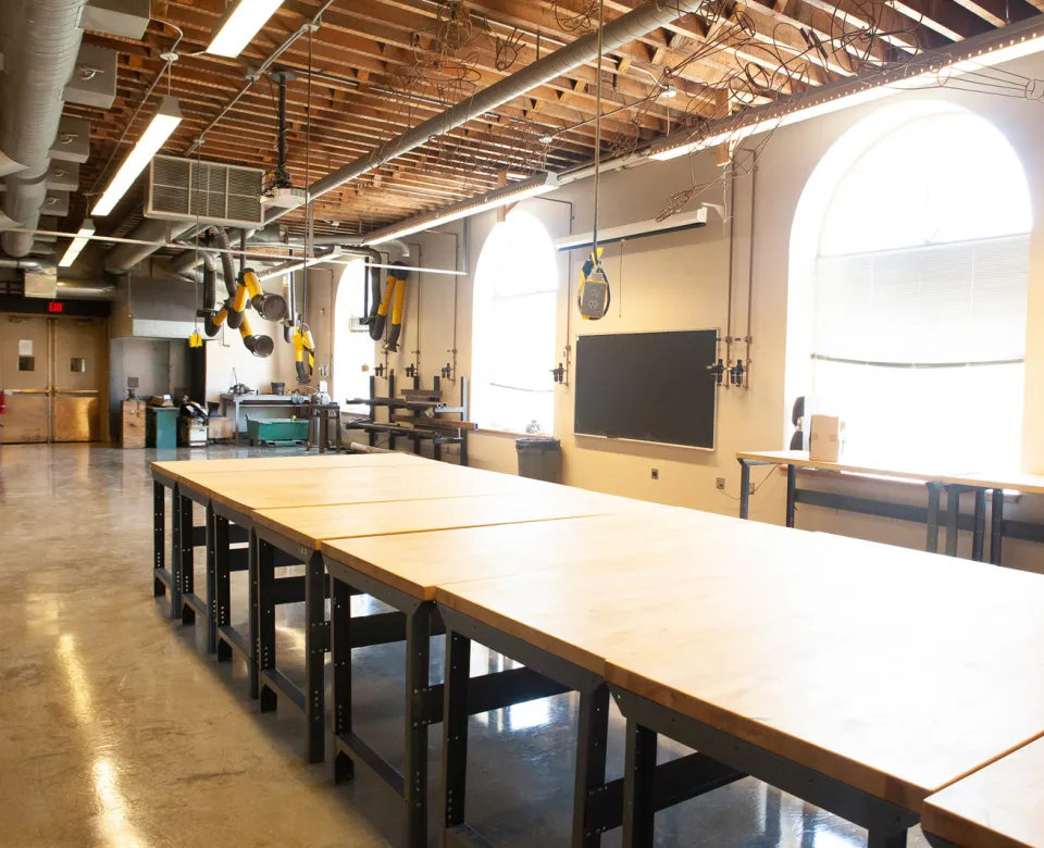 Sculpture studio with large table, windows and equipment.