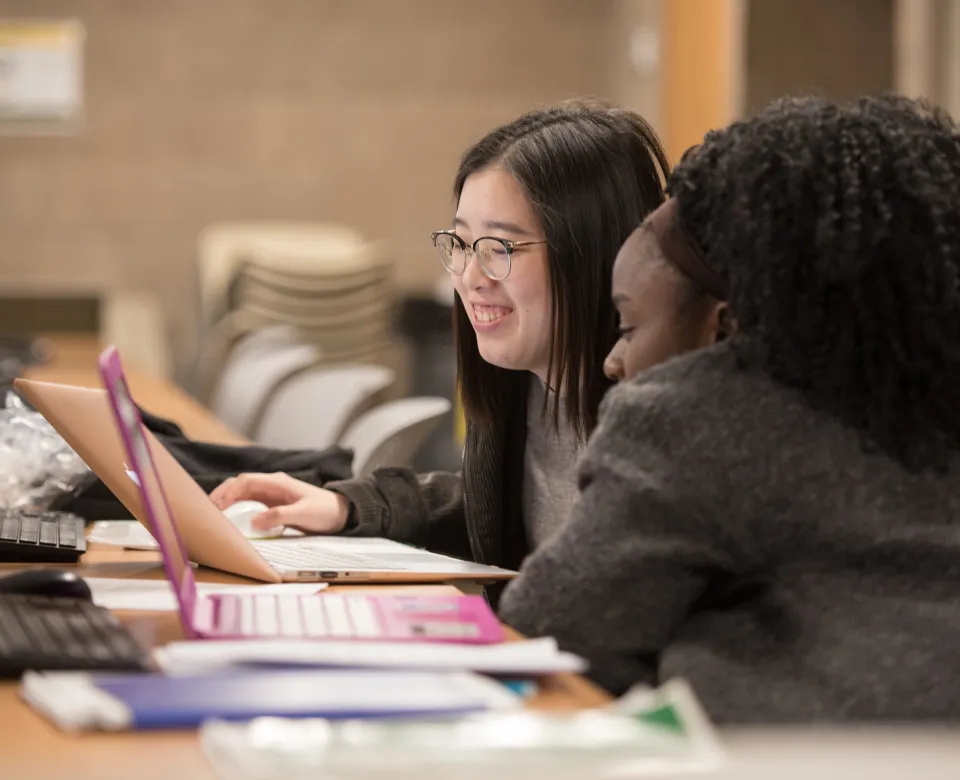 Two students looking intently at a laptop.