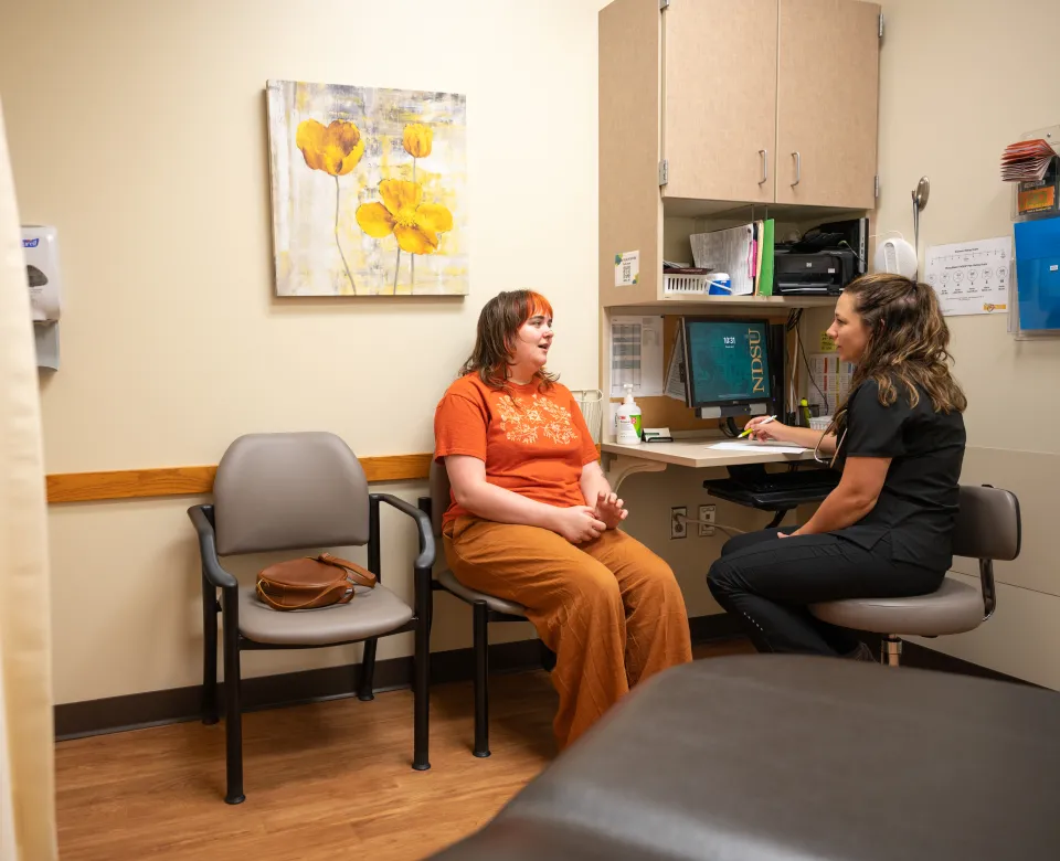 Student and nurse talking in an exam room.