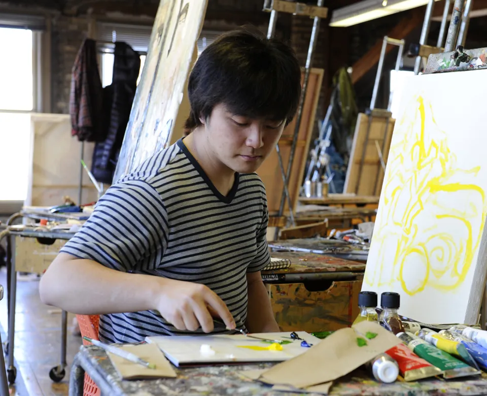 Student working with yellow paint on canvas.