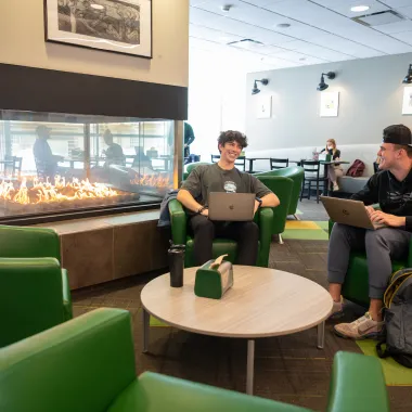 two students lounging next to a fire in a dining center