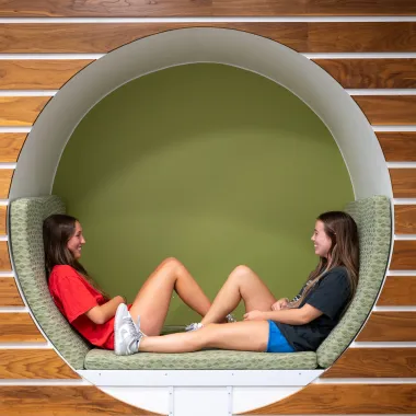 Two students lounging in a circular cubby in Cater Hall
