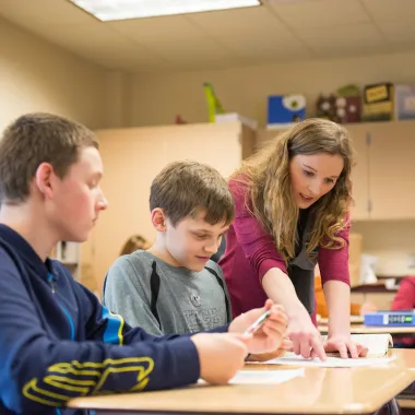 teacher helping students with a project in class
