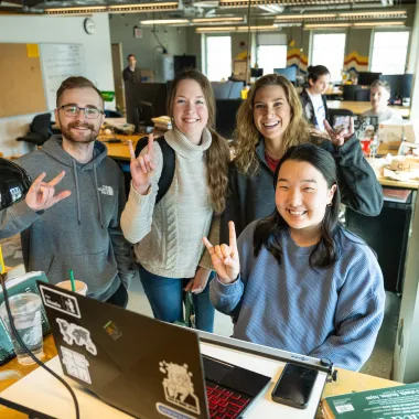 Landscape Architecture Students smiling confidently at camera holding the 'horns up' hand gesture
