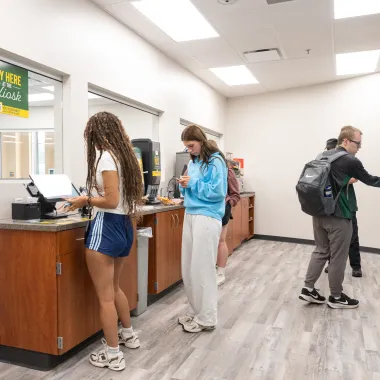 Three students inside of the Micro Market at Barry Hall purchasing food 