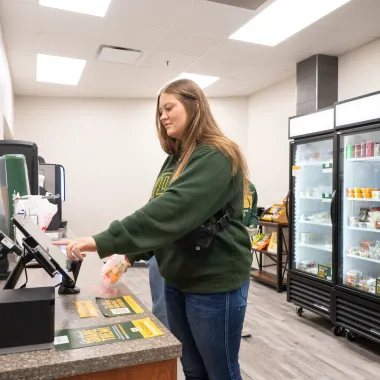 Female student in a green sweatshirt checking out at the Micro Market