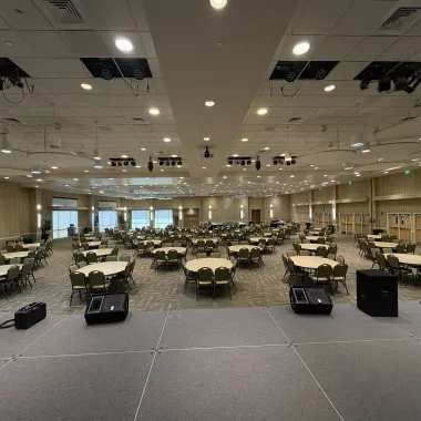 Oceti Sakowin Ballroom arranged with round tables for banquet view from stage
