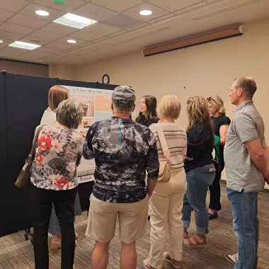 Group of people looking at a presentation board at the CCPAC Open House Spring 2024