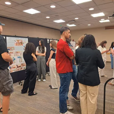 Group of people looking at a presentation boards at the CCPAC Open House Spring 2024