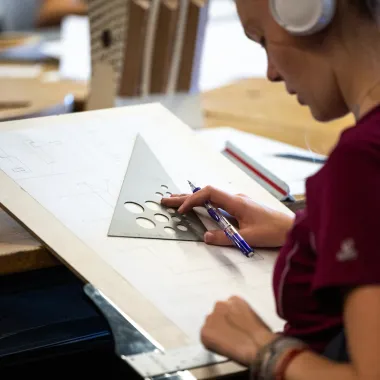 Student working with drafting tools in architecture studio.
