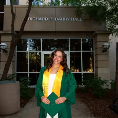 graduate in front of Barry Hall 