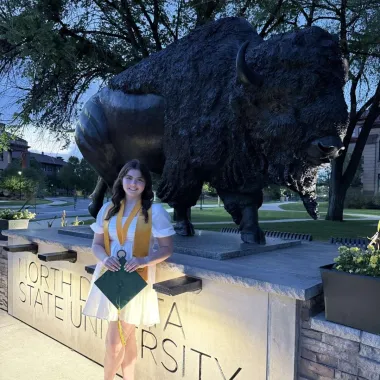graduate in front of bison statue