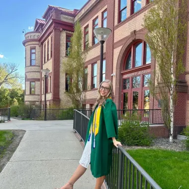 graduate in front of Minard Hall