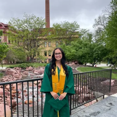 graduate standing in front of Babbling Brook