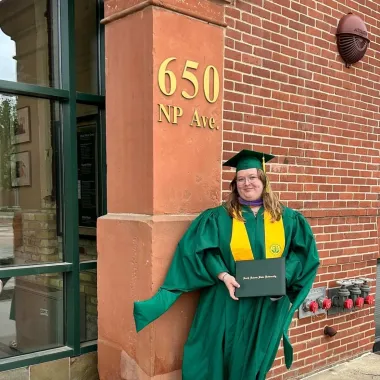 graduate standing in front of Renaissance Hall