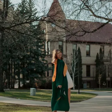 graduate standing in front of Old Main